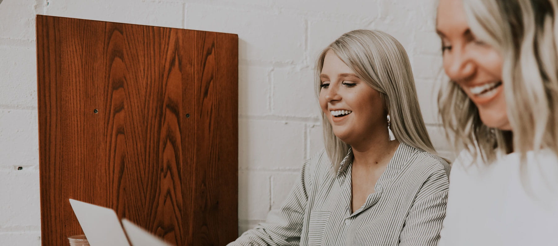 Woman sitting together and laughing while looking at a laptop computer