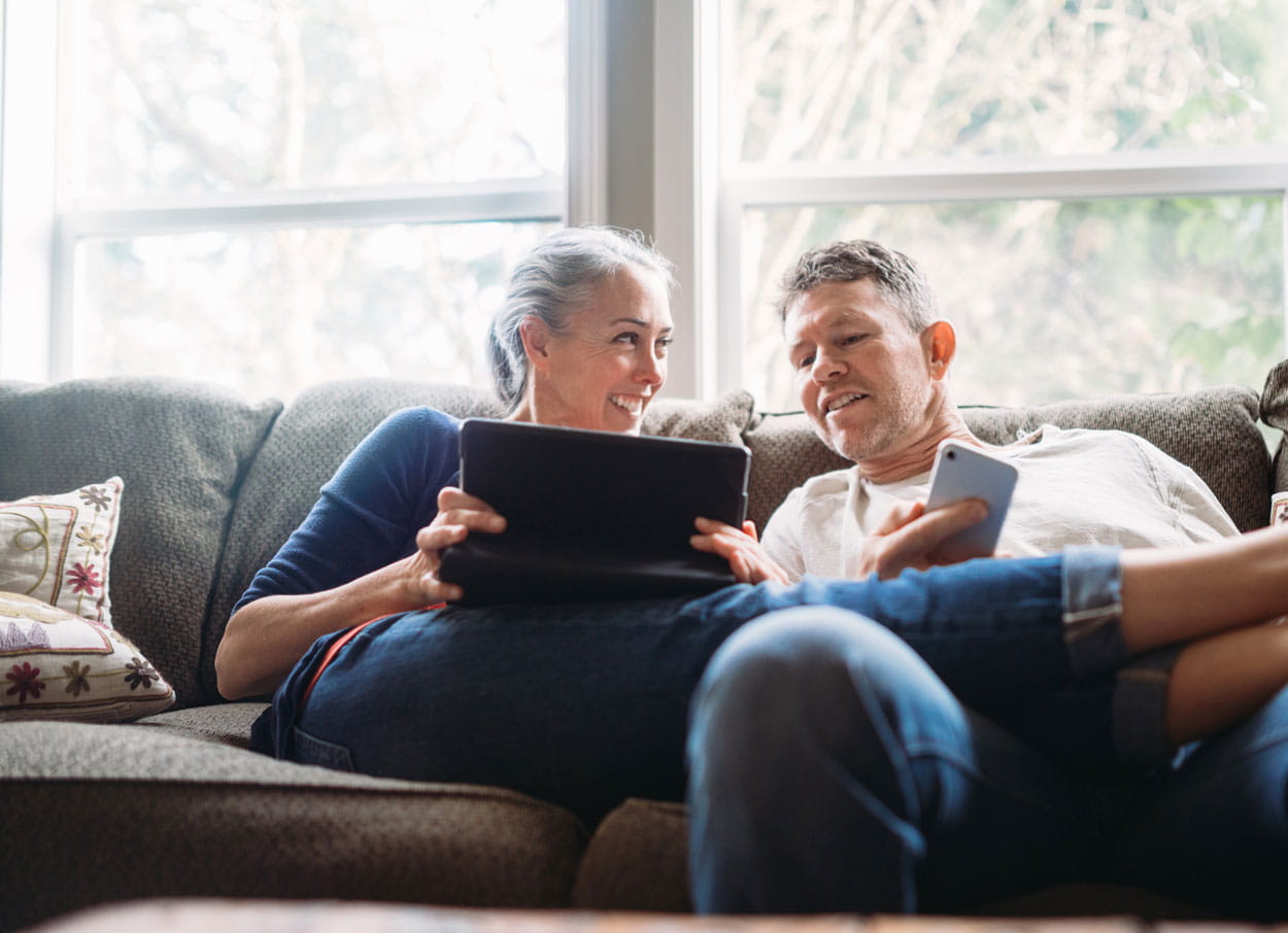 Couple on the couch looking at a tablet together