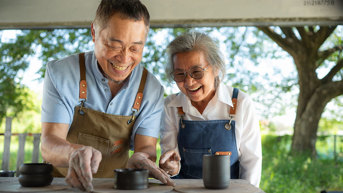 Man and woman smiling doing pottery on a deck