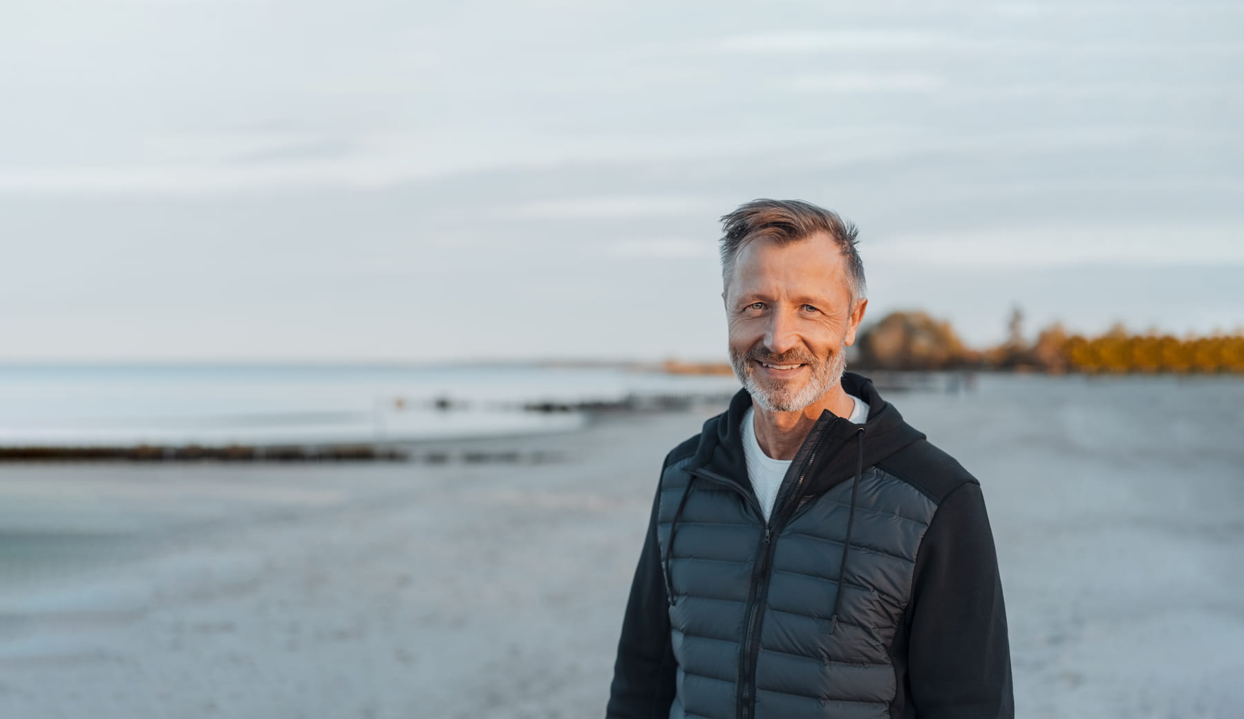 Man standing on beach and smiling at the camera